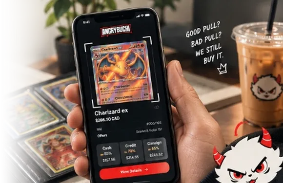 Hand holding phone scanning a Charizard trading card beside binder pages and AngryBuchi iced coffee on desk